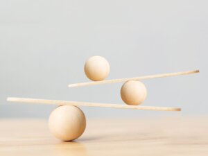 Image of wooden spheres balancing on sticks, symbolizing the balance and stability brought by resonating movements in the human body.